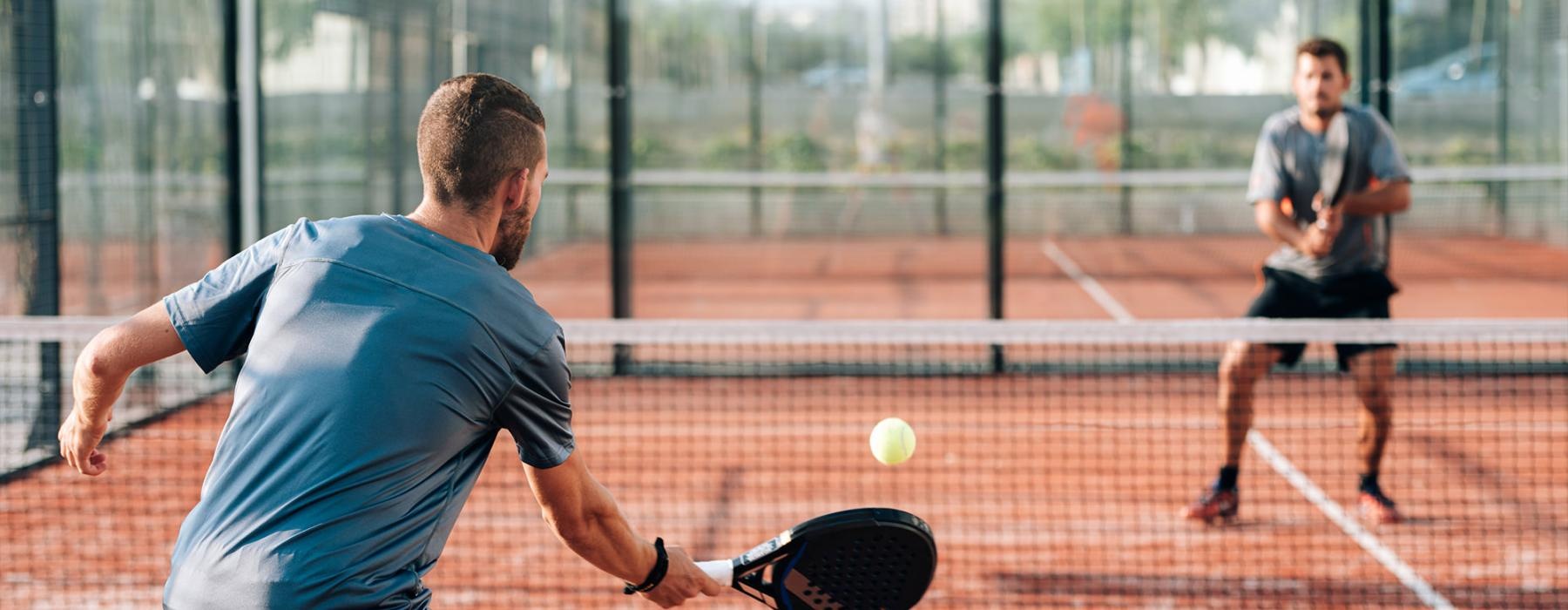 a person hitting a ball with a pickleball paddle to another person