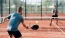 a person hitting a ball with a pickleball paddle to another person